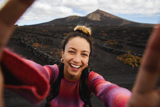 Happy woman taking selfie with scenic landscape in background