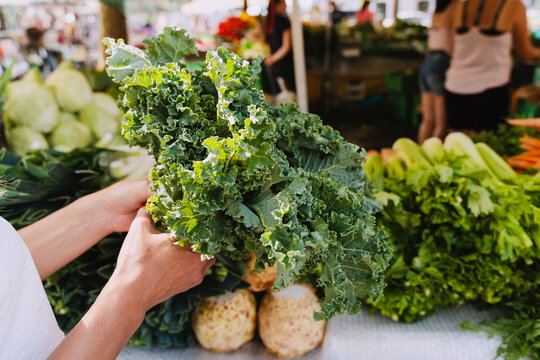 Woman buying fresh green kale vegetable in farmer's market