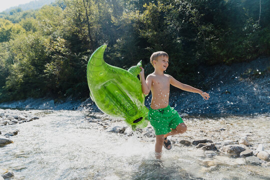 Child playing with inflatable toy in river on summer vacation