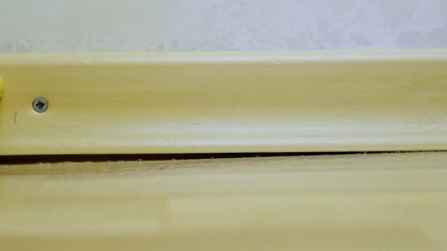 Home cleaning of baseboard edges. Focused cleaning of baseboard seams with sponge and gloves. Practical household scene involving gloves and sponge for detailed cleaning tasks