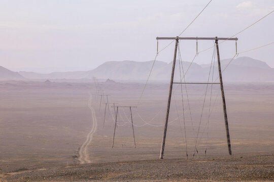 A power line stretches across a silent volcanic desert in Iceland