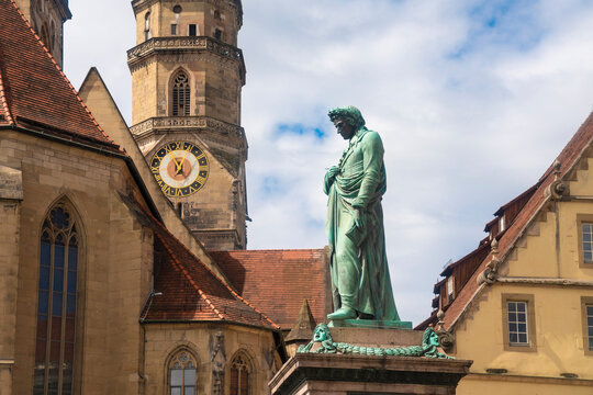 Germany, Baden-Wurttemberg, Stuttgart, Statue of Friedrich Schiller at Schillerplatz with bell tower of Stiftskirche in background
