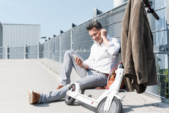 Businessman with E-Scooter and smartphone