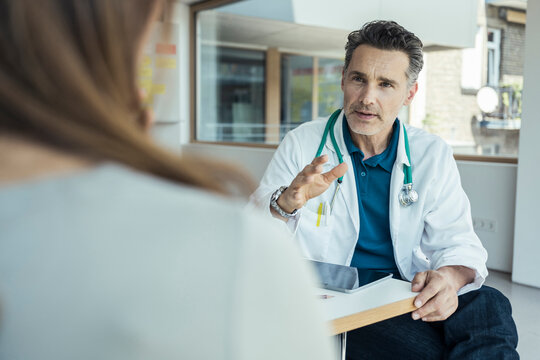 Male doctor explaining female patient while sitting in office