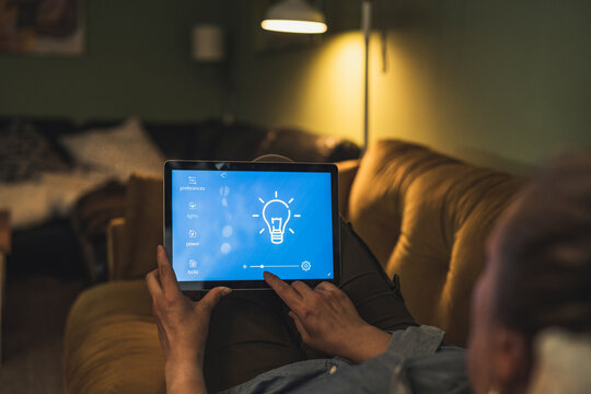 Woman adjusting lighting equipment through digital tablet at home