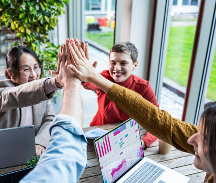 Team celebrating success with high five in modern office