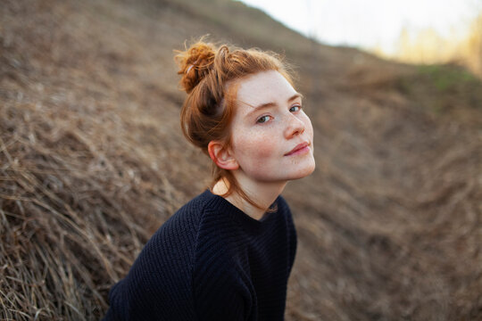 Portrait of teenage girl with red hair and freckles in a sunny spring park