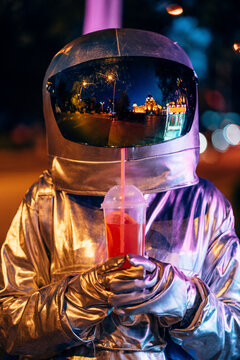 Spaceman in the city at night with takeaway drink