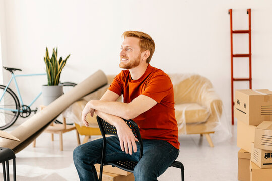 Smiling man sitting on chair in living room at home