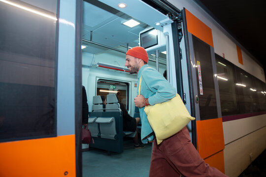 A smiling man exits a subway train in Barcelona after work