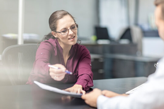 Woman showing contract to client at desk