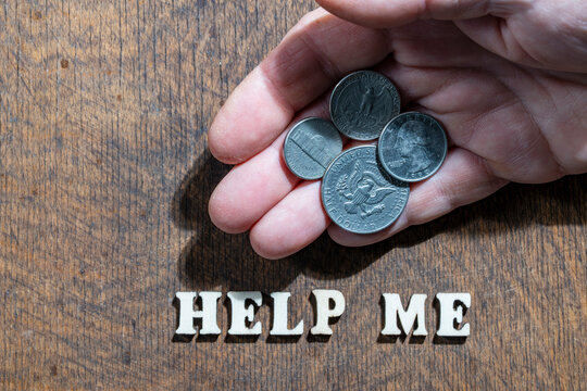 Man holding US coins over help me text, closeup. Top view of open hand holding American quarter and half dollar coins above wooden words help me, symbolizing financial crisis, poverty and recession