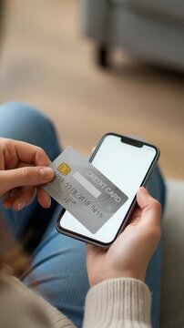 Woman holding a credit card up to a smartphone for contactless mobile payment. closeup lap shot of hands tapping the card on the phone screen, online banking and digital transaction concept.