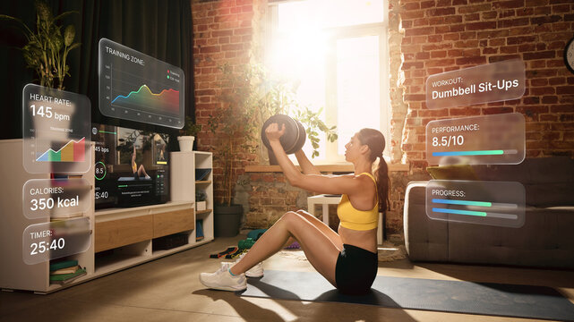 Woman performing weighted sit up with virtual workout analytics at home. Concept of digital coaching, workout statistics, fitness applications, smart training and healthy lifestyle.