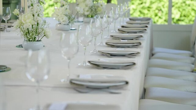 Beautifully arranged wedding reception table featuring white flowers, glassware, and plates, creating an inviting atmosphere for guests to enjoy