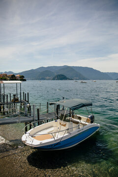 Small motorboat moored at the waterfront of Lake Como with mountain scenery in Varenna, Lombardy, Italy. Editorial use only.
