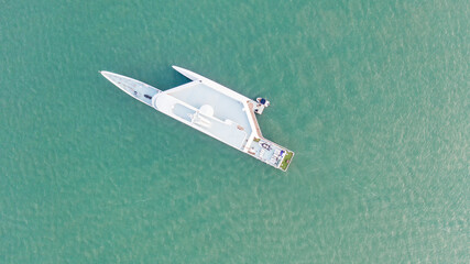 Top-down aerial drone view of a modern luxury yacht anchored in clear turquoise ocean waters with a private tender boat alongside © Rastim