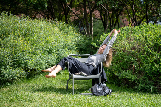 Lazy woman resting on grass outside, sleeping outdoors, dozing bathing in warm sunshine. Relaxing female recreating, napping at open fresh air under summer sun rays. Lady quietly sleeping at park