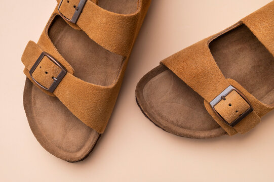 Close-up of brown leather summer sandals on beige background. Unisex open-toe shoes, stylish, fashionable sandals for everyday wear, leisure, and travel. Fashion, wardrobe essentials