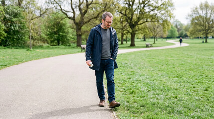 Obraz premium Man walking thoughtfully, avoiding grass, in a park setting 