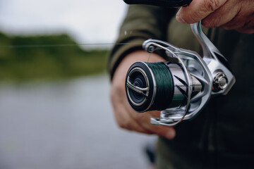 A spinning rod with a spinning reel in the hands of a fisherman © smiltena