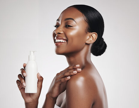 Radiant Black Woman Smiling While Holding a White Skincare Product Bottle