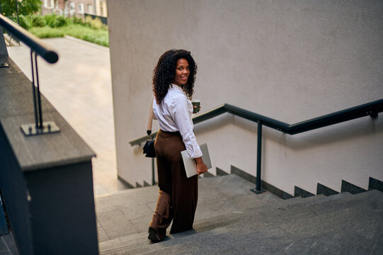 African American Woman Walking Down Urban Stairs With Laptop Coffee Professional Confidence