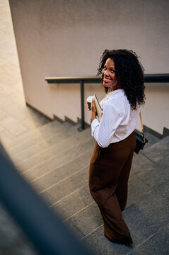 Confident African American Business Woman Going Down Urban Stairs With Coffee And Tablet Smiling At Camera