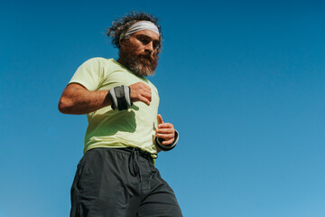 Fototapeta premium Athletic bearded man running with wrist weights outdoors