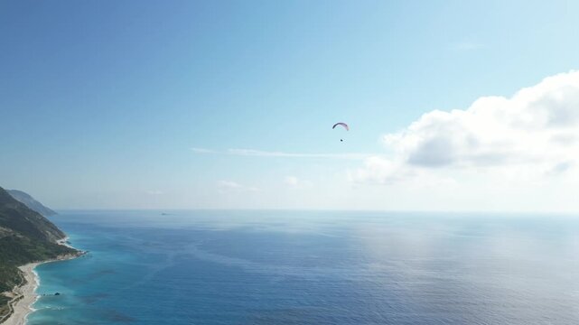 Paraglider flying high above the deep blue sea