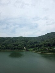 Fototapeta premium 남양주 오남저수지의 여름, 초록이 짙은 산과 강, 하늘과 구름, 멋진 자연 배경