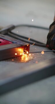 Worker performing stick welding on a metal frame creating hot sparks and molten metal