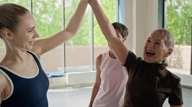 Caucasian young adult, middle aged, and senior women talking and giving high fives in fitness studio. Footage ideal for active aging, wellness, and community marketing campaigns