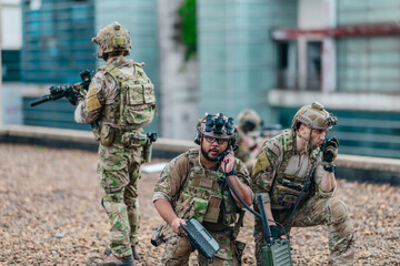 Fototapeta premium Military tactical team reviews mission plan on rugged laptop during outdoor field briefing
