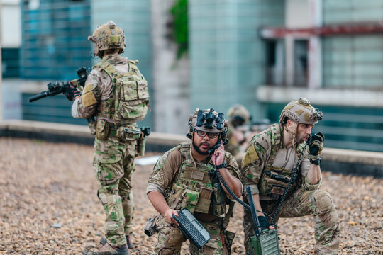  Military tactical team reviews mission plan on rugged laptop during outdoor field briefing