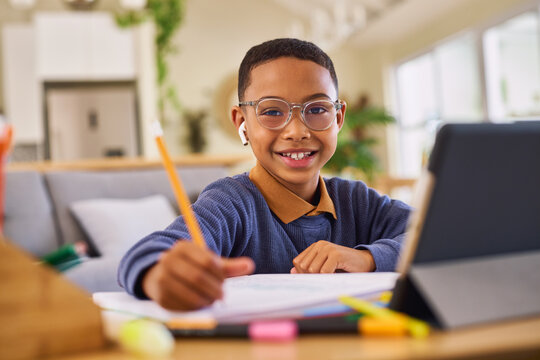 Portrait of little black schoolboy studying at home on digital tablet