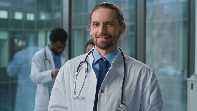 Portrait smiling Caucasian man doctor in medical uniform posing in clinic. Male pediatrician therapist practitioner surgeon medicine worker professional smile looking at camera working in hospital