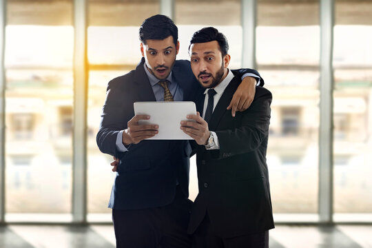 Corporate employees in formal business suit looking at a digital tablet and amazed.