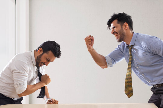 Two corporate employees in formal clothing with one of them celebrating his win in match.