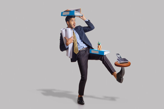 Portrait of an employee in formal clothing carefully balancing files,Charts and a wood piece with mobile.