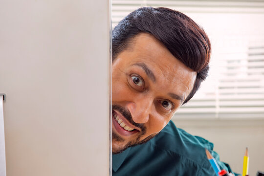 A corporate employee's face peeping out from the desktop screen in office.
