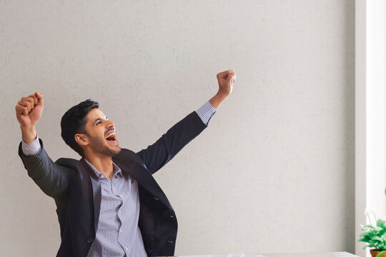 Portrait of a corporate employee in formal business suit clenching fists to celebrate his success.