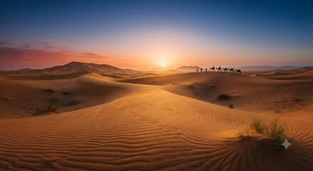 Fototapeta premium Golden sunrise over desert sand dunes with a camel caravan walking in the distance.