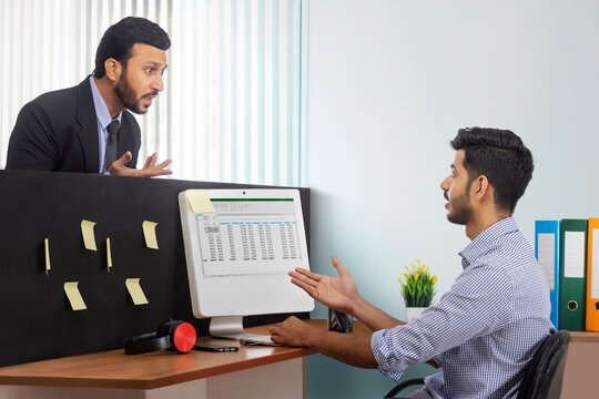 An angry boss in formal suit and a subordinate corporate employee arguing at the workdesk.