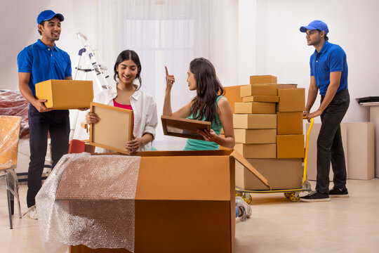 Delivery boys moving carton boxes and helping girls in packing