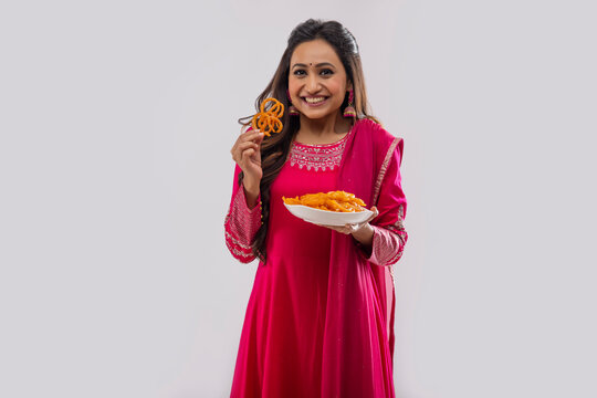 Indian woman in pink salwar Standing with a plate of Jalebi on festival