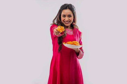 Indian woman in pink salwar offering Jalebi on festival