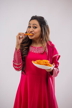 Indian woman in pink salwar eating Jalebi on festival