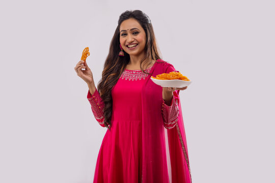 Indian woman standing with a tray full of jalebi on festival