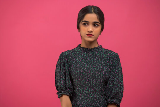 Portrait of young girl looking away against pink background